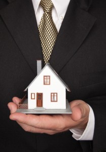 Businessman with Coat and Tie Holding House.